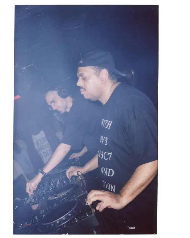 Deux DJ en t-shirt noir aux platines du Rex Club, dans un halo bleu