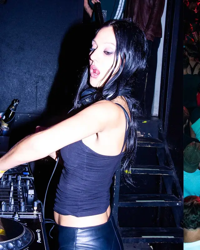 Une DJ aux cheveux noirs, bras levé, derrière les platines du Kilomètre25