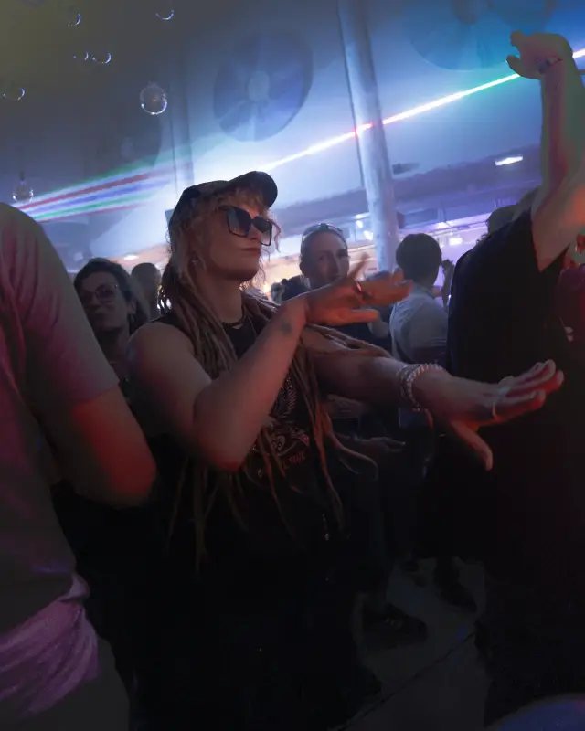 Une danseuse en casquette au milieu de la foule du 211, sous les lasers